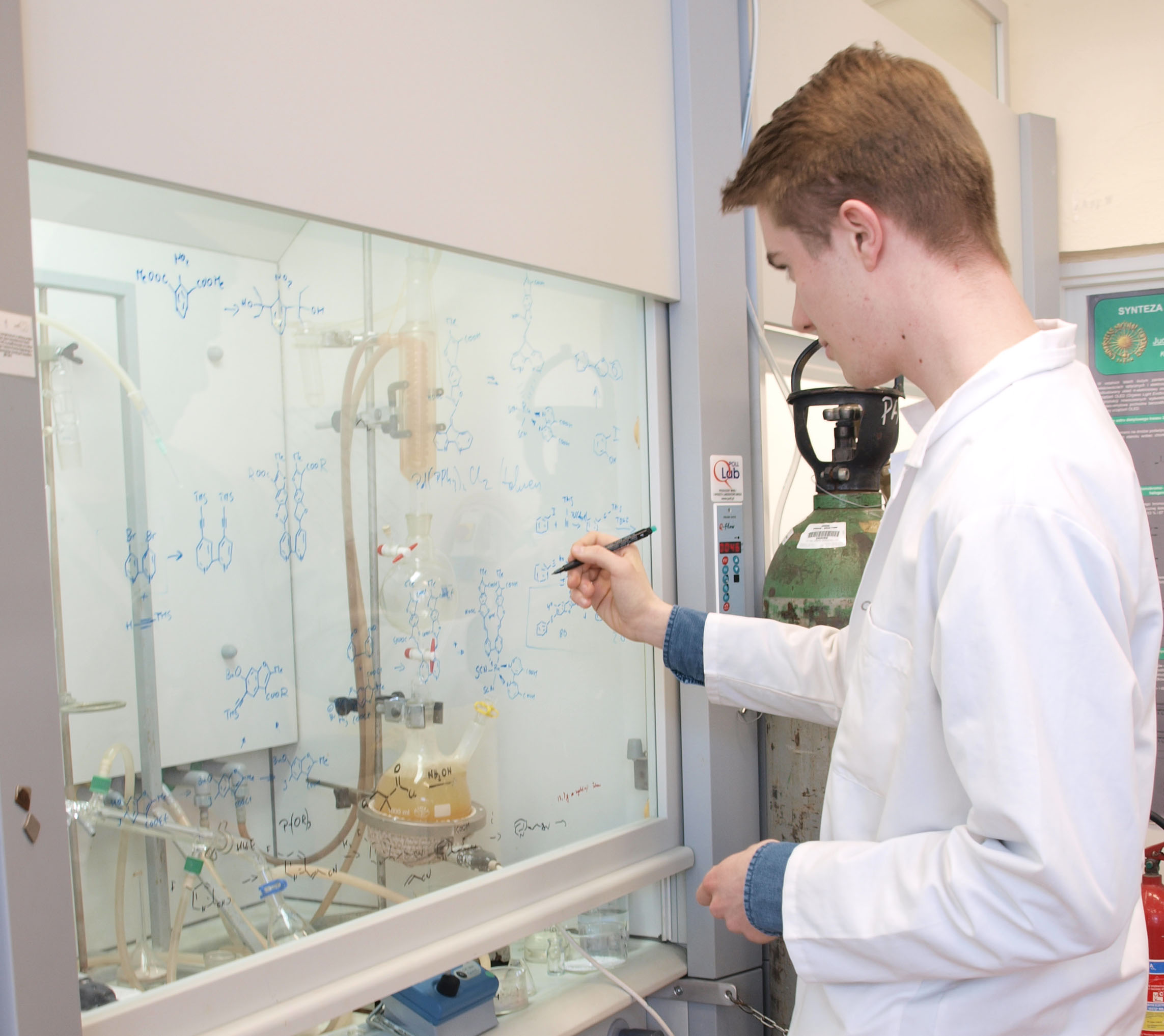 A student in lab coat standing in front of a fume-hood